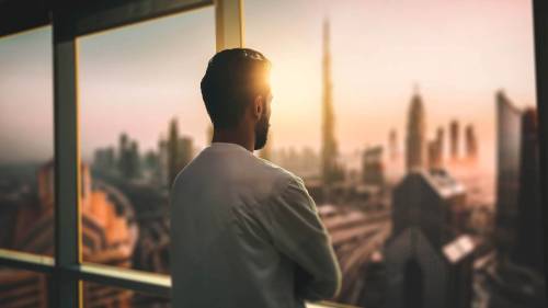man looking out of window with view of a city